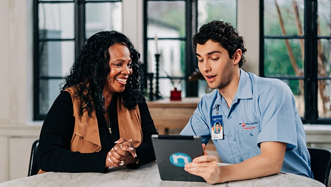A Mr. Appliance technician talks to a client while sitting at a table.