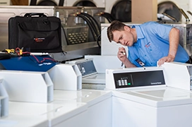 Mr. Appliance service professional inspecting the back of a commercial washing machine.