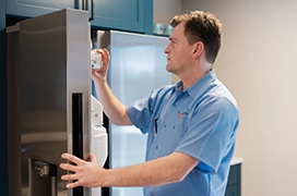 Mr. Appliance service professional inspecting the ice maker of a refrigerator.