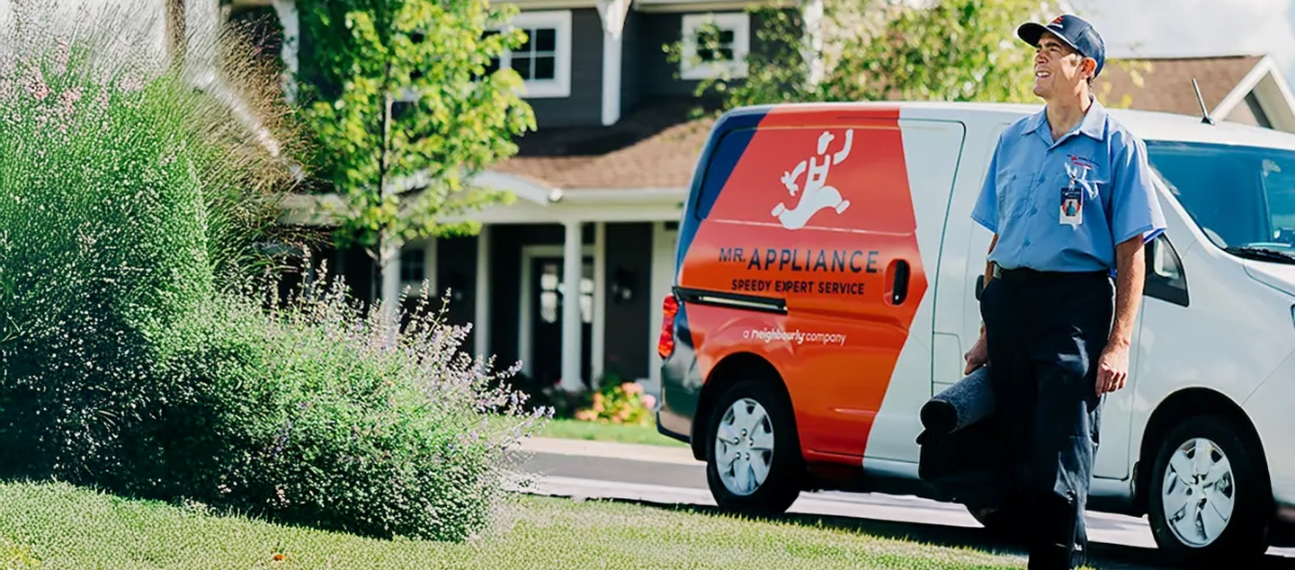 Male tech smiling in front of branded van.