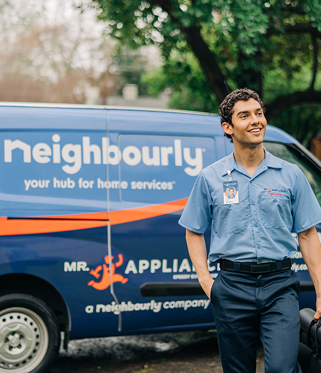 Mr. Appliance technician smiling in front of branded van. 