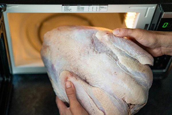 Raw turkey being put into a microwave