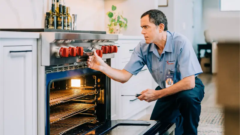 Mr. Appliance technician working on repairing an oven.