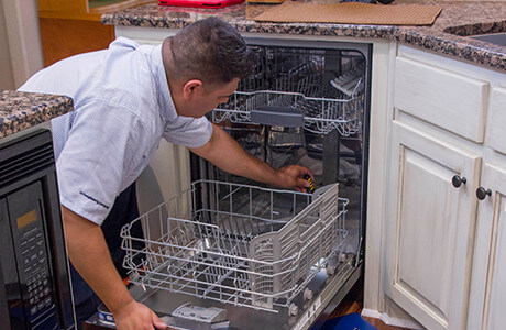 Technician looking inside a dishwasher to troubleshoot and diagnose the problem.