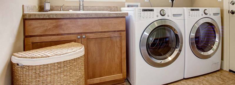 Gray washing machine and dryer beside sink in tidy home laundry room.